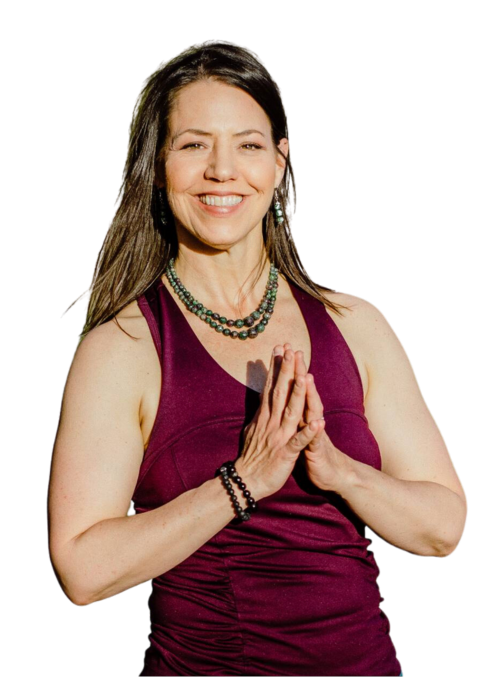 White woman facing right with shoulder-length brown hair smiling at the camera with palms together in front of her heart.