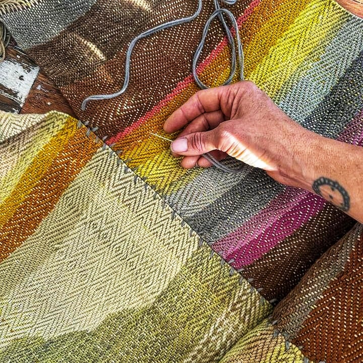 Pranayama - Unexpected Benefits of Breathing as a Spiritual Practice- Hand stitching a colorful woven fabric with intricate patterns and textures using needle and thread.